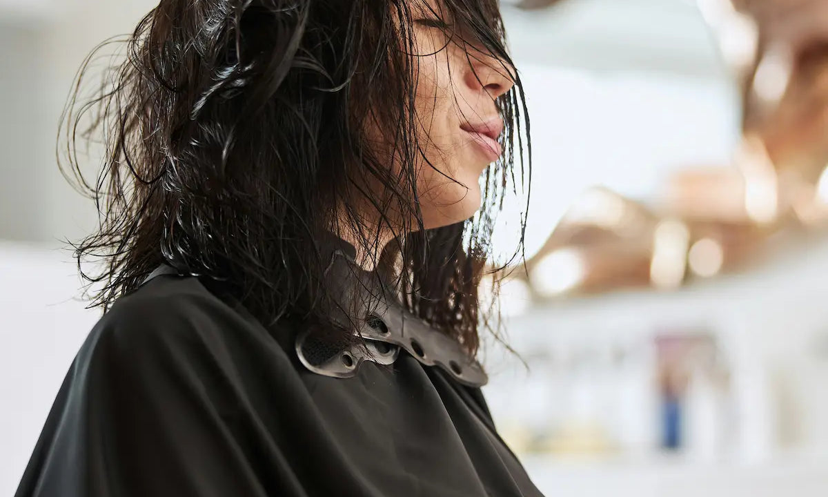 A stylist brushing through a client's wet hair at a salon before a haircut