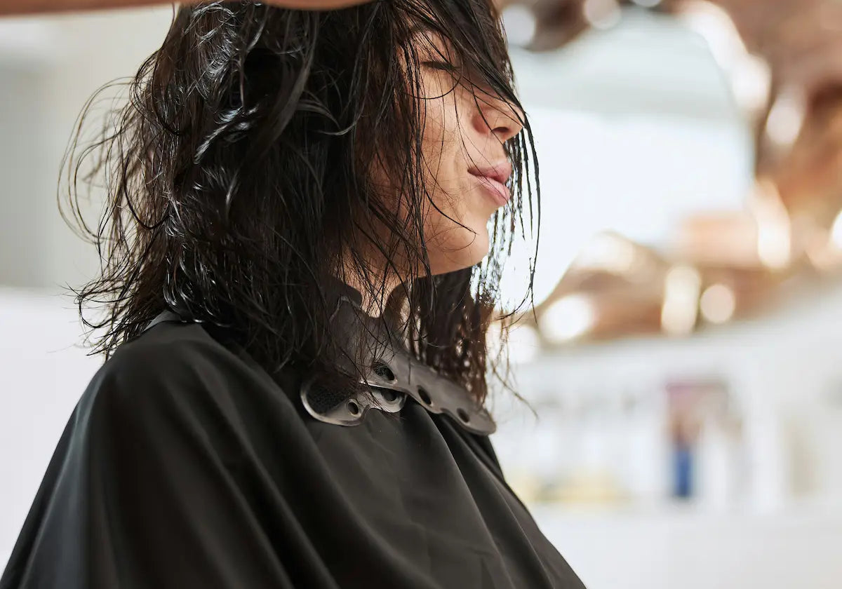 A stylist brushing through a client's wet hair at a salon before a haircut