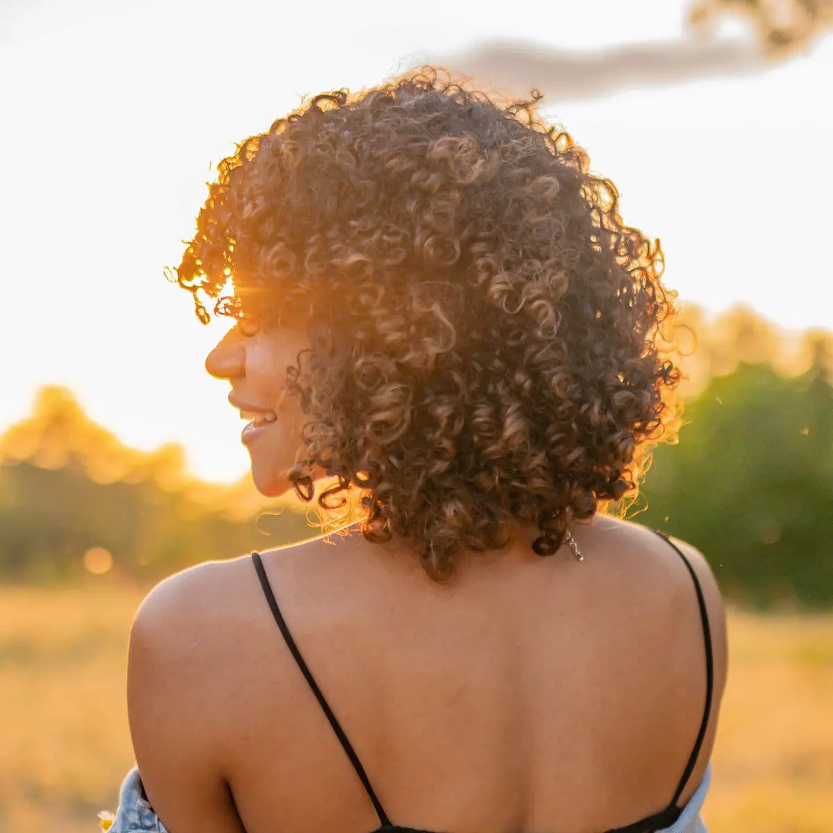 Healthy, defined curly hair glowing in the summer golden hour sun