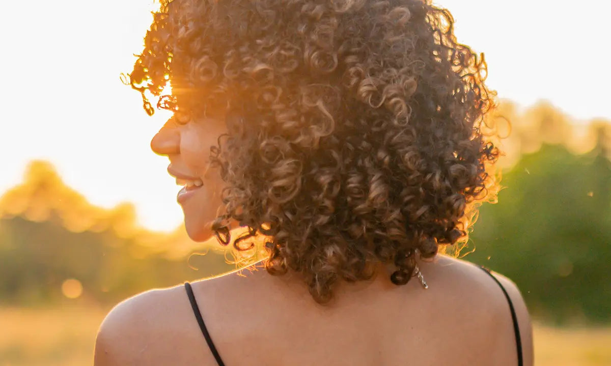 Healthy, defined curly hair glowing in the summer golden hour sun