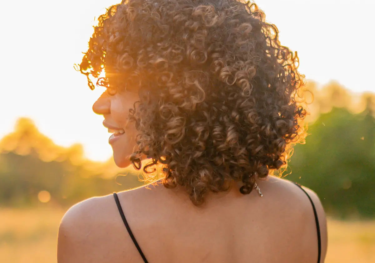 Healthy, defined curly hair glowing in the summer golden hour sun