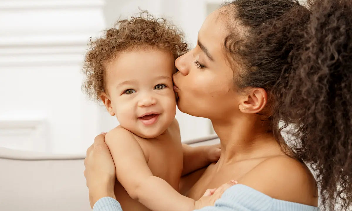 New mother kissing her smiling baby during the postpartum period