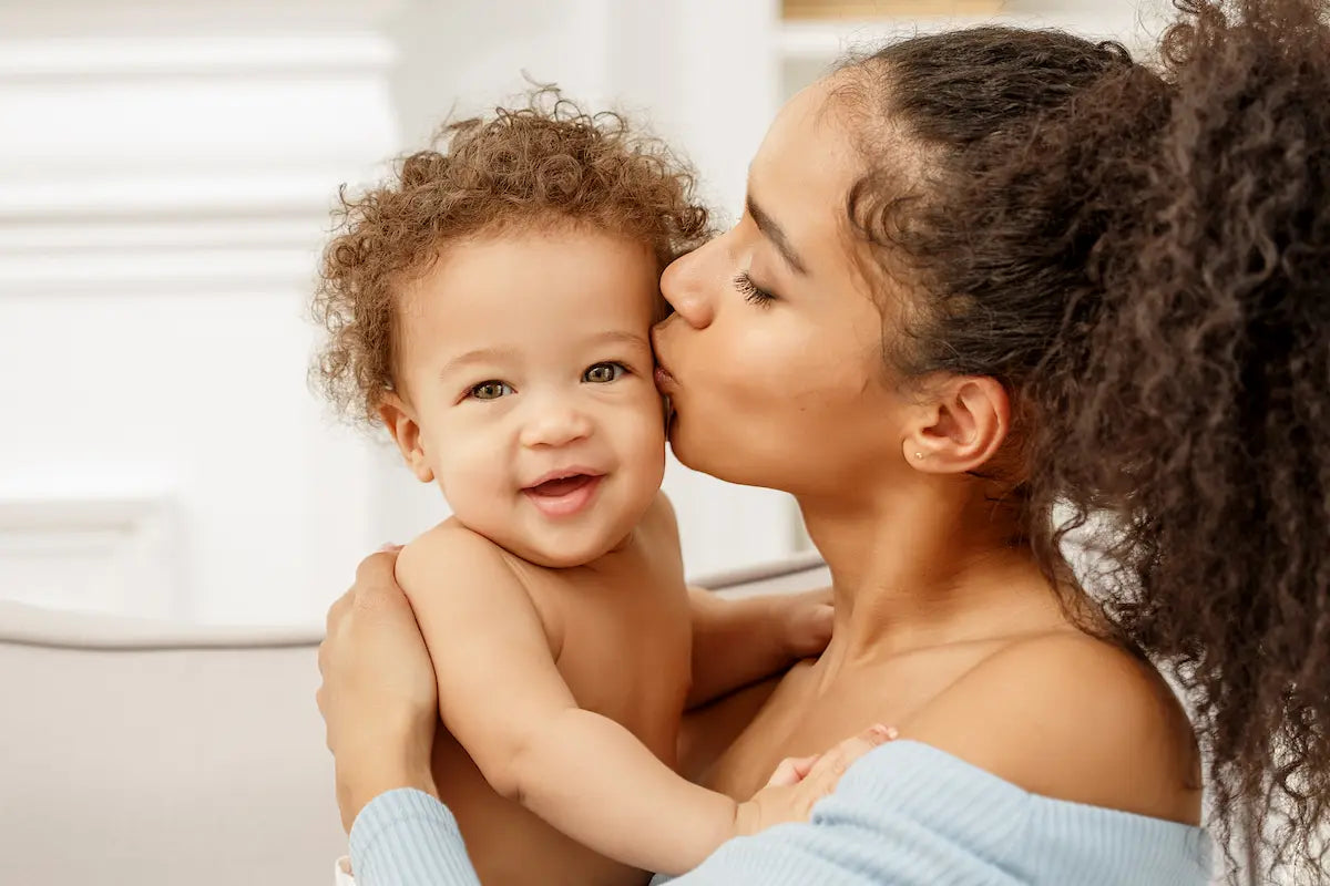New mother kissing her smiling baby during the postpartum period