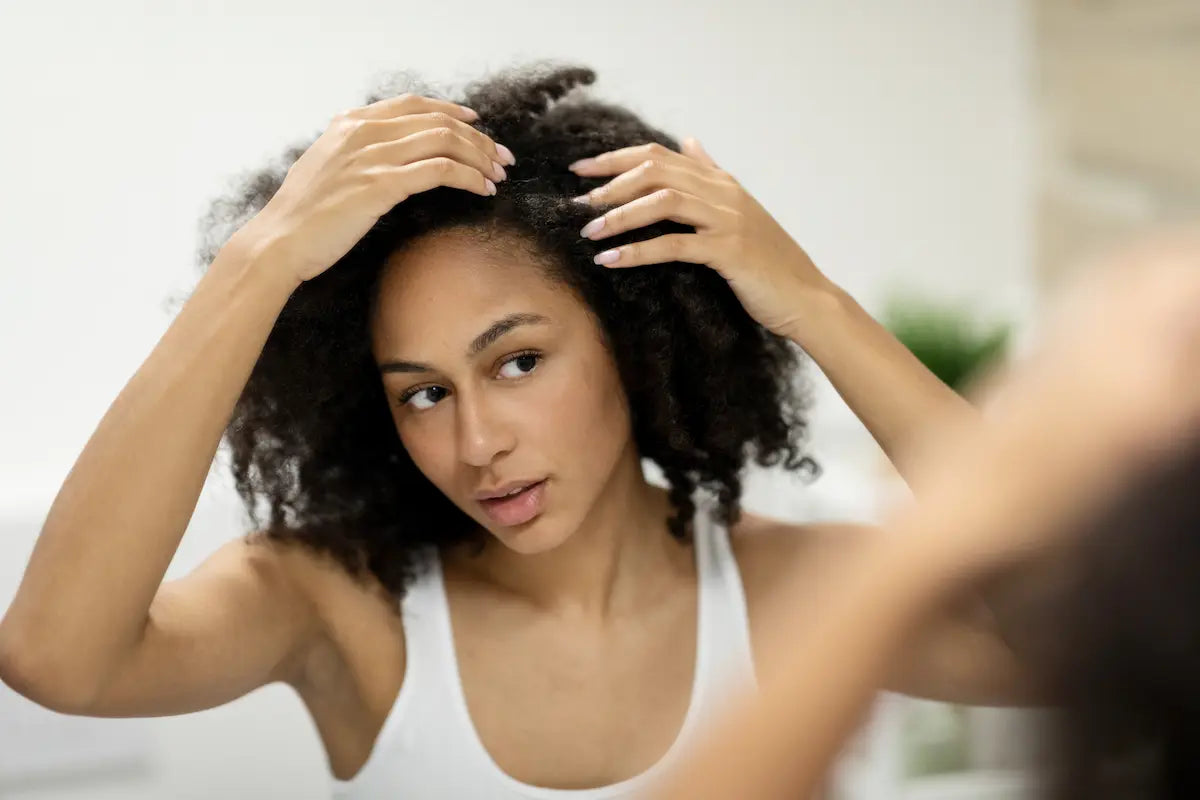 Woman checking her hair parting in the mirror for scalp health.