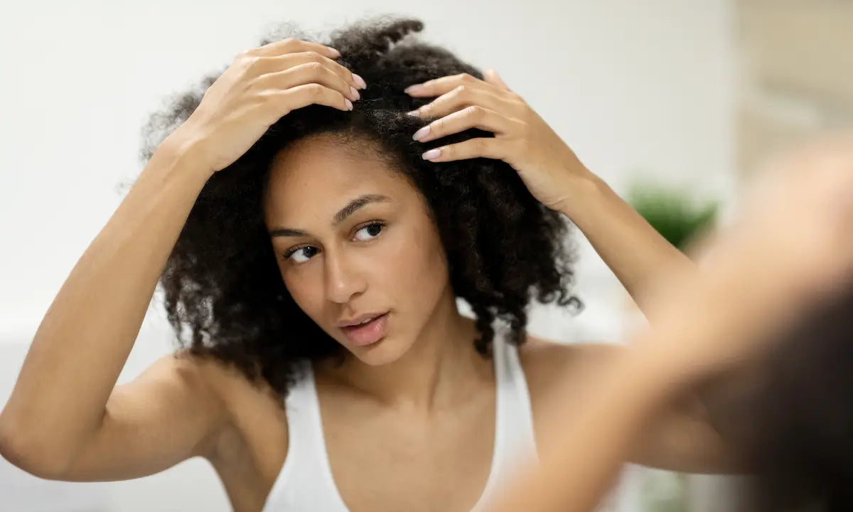 Woman checking her hair parting in the mirror for scalp health.