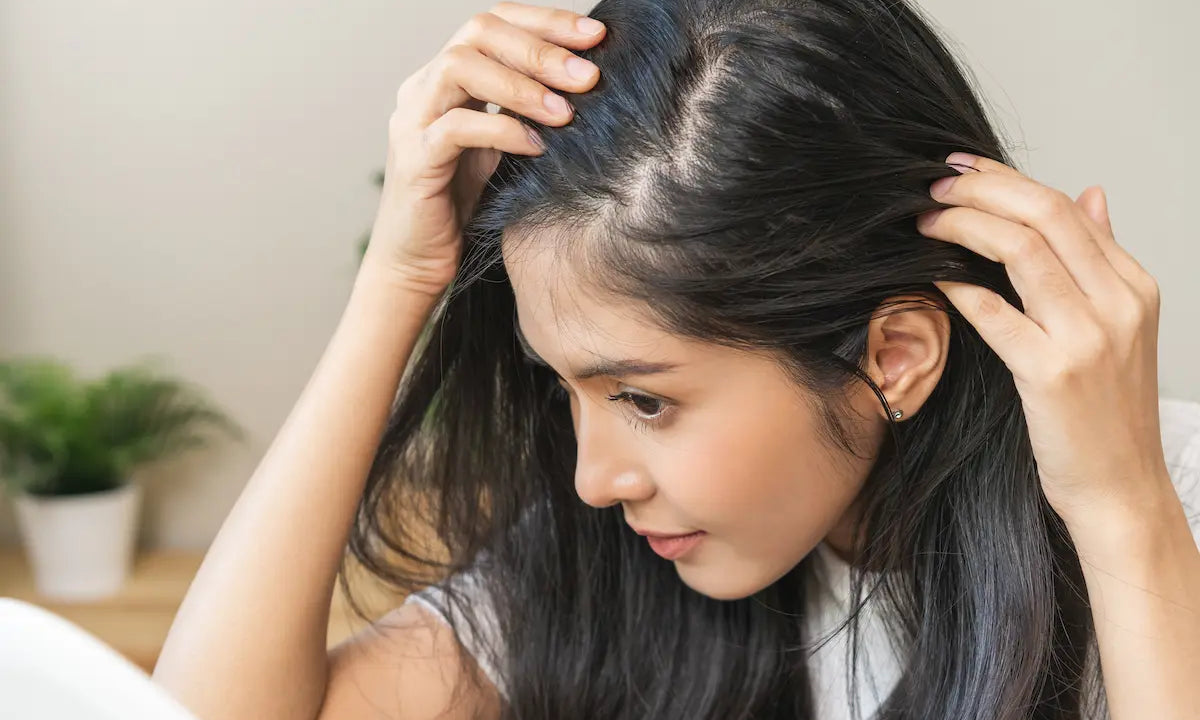  Woman looking in a mirror examining her hair parting for dry or oily scalp symptoms