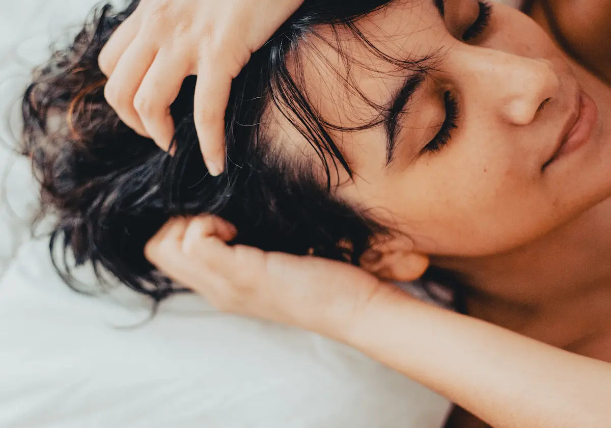 Woman sleeping comfortably in bed with damp dark hair on a white pillow