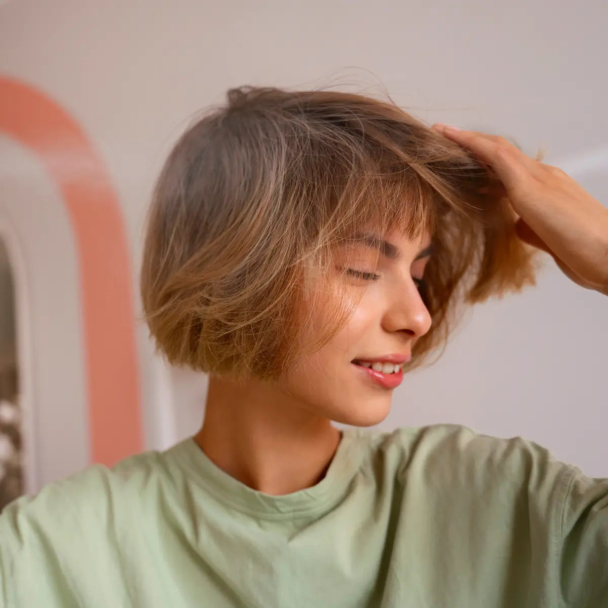 Woman styling short blonde hair for volume after applying dry shampoo