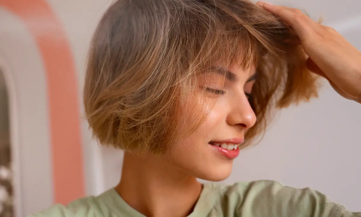 Woman styling short blonde hair for volume after applying dry shampoo