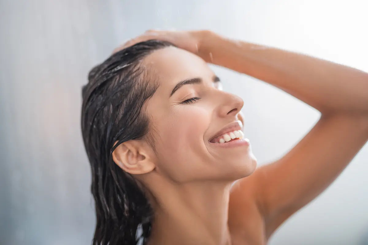 Woman washing her hair in the shower to maintain a healthy, balanced scalp pH