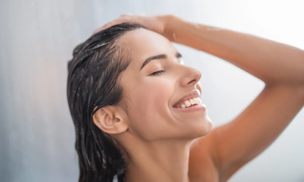 Woman washing her hair in the shower to maintain a healthy, balanced scalp pH